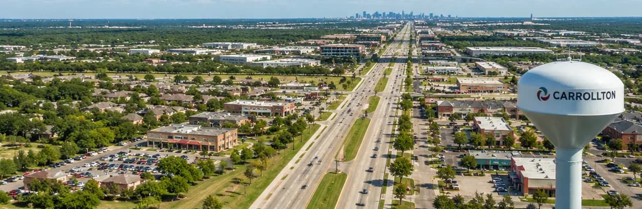 An aerial view over Carrollton, Texas with the city water tower in the foreground and the Dallas skyline on the horizon