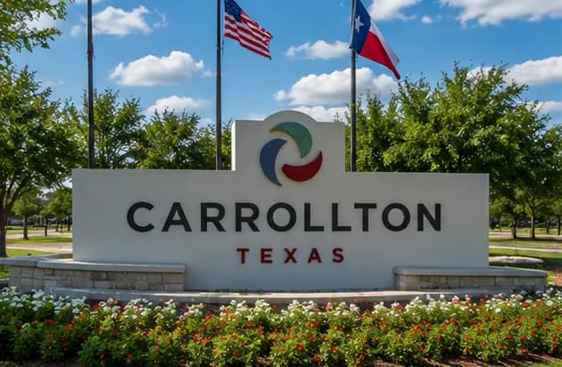 The City of Carrollton, Texas monument sign with the United States and Texas flags behind it