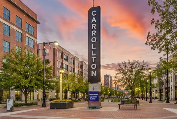 Downtown Carrollton Square at dusk with the illuminated Carrollton marker and brick storefronts
