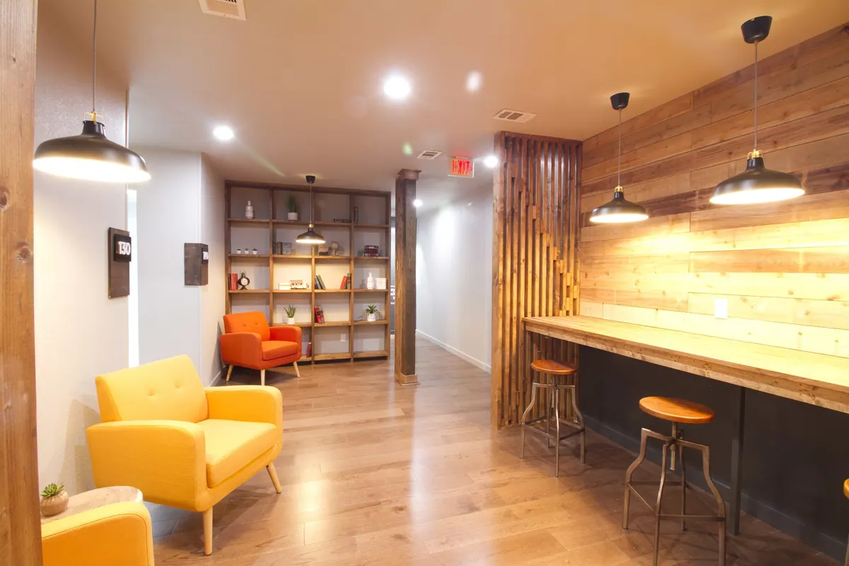 A common area with a timber feature wall, bar counter and lounge seating inside 3712 Old Denton Rd, Carrollton