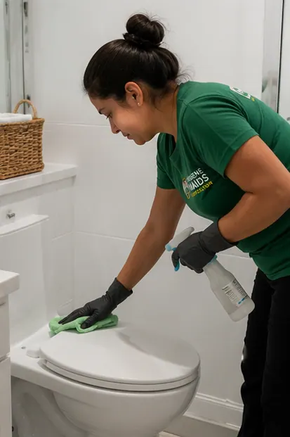 A cleaner disinfecting a toilet in a bathroom