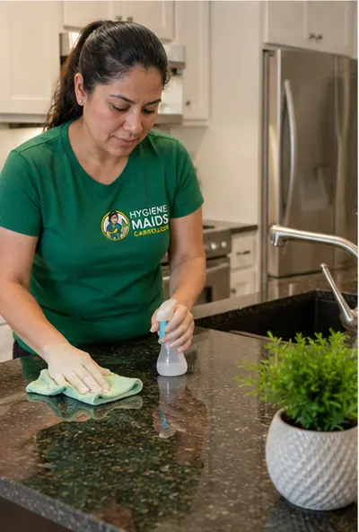 A cleaner wiping a dark granite kitchen counter